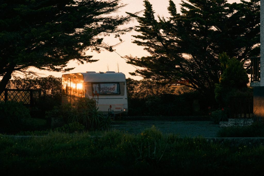 a trailer parked in front of some trees at sunset